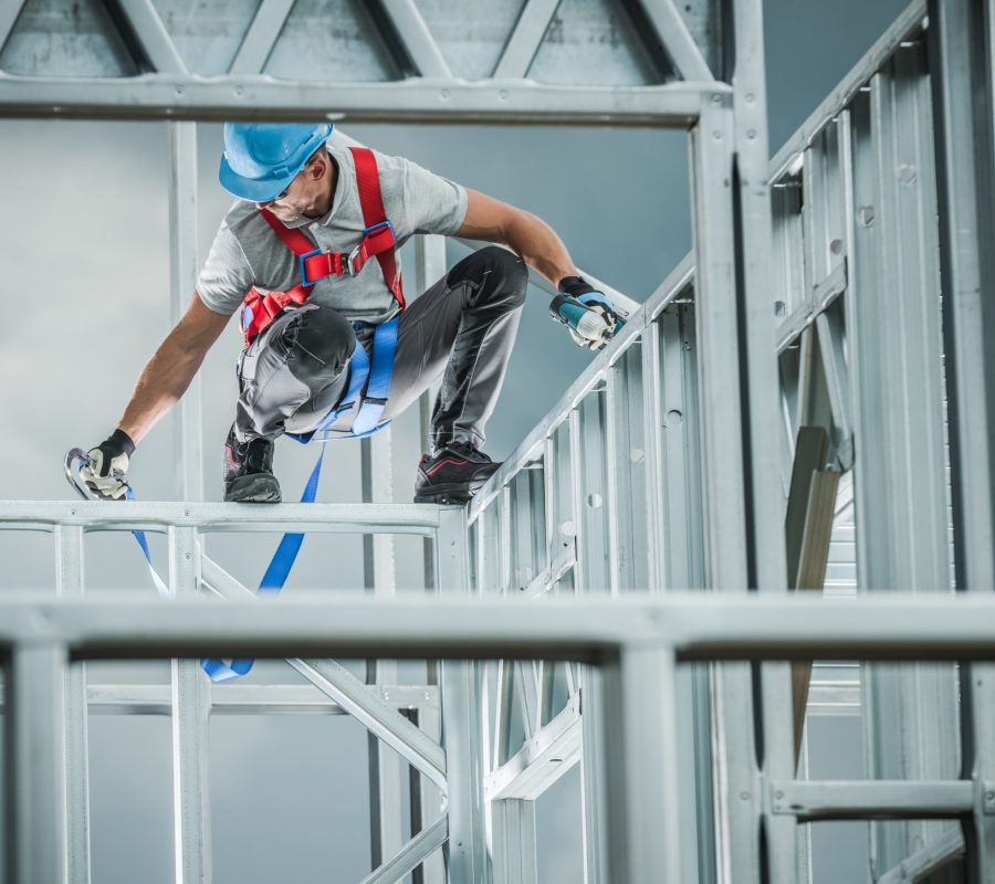 Caucasian Contractor Building Skeleton Steel Frame with Help of Safety Harness Equipment. Industrial Theme.